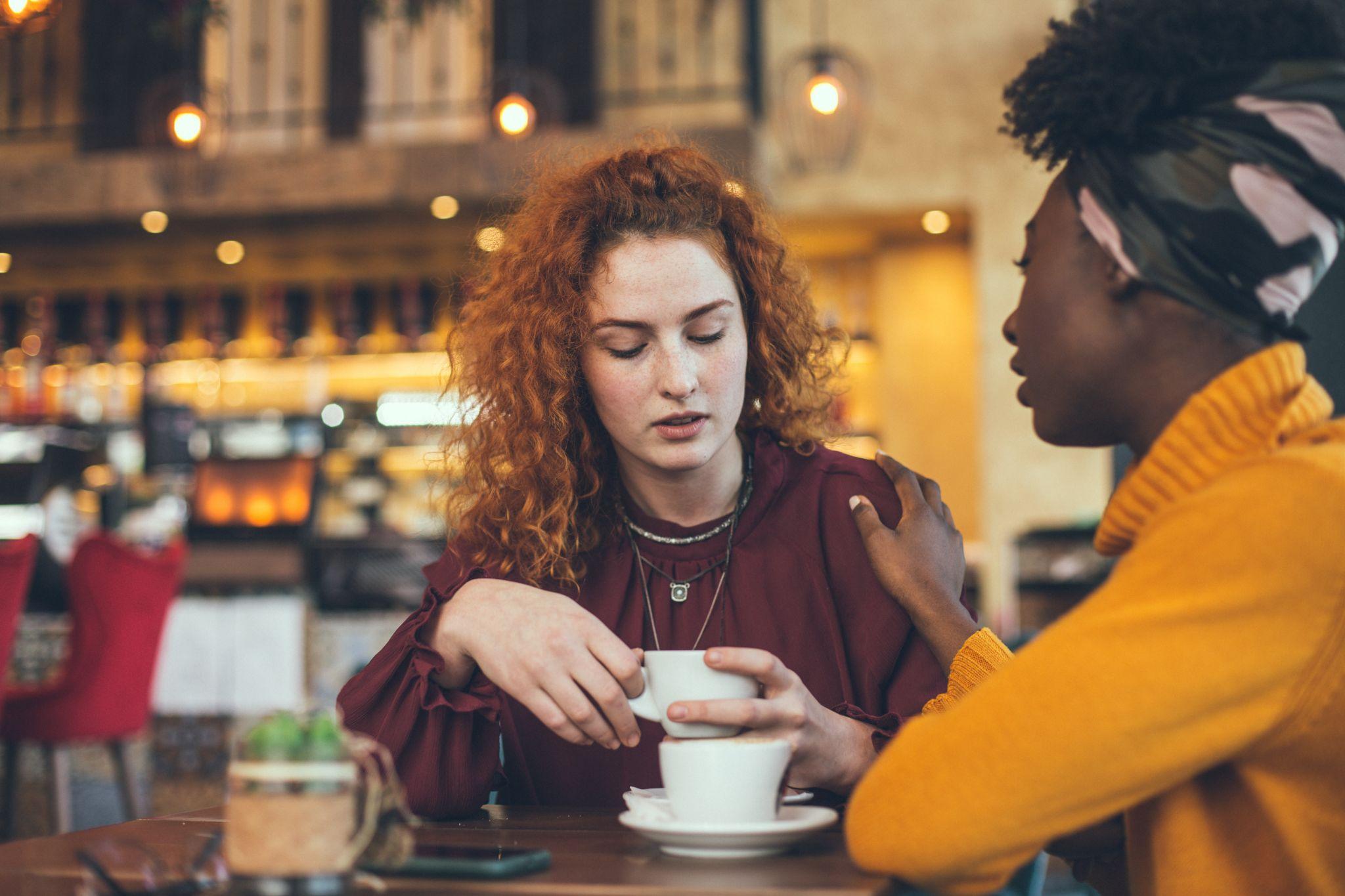 A young woman is talking with a female friend about her problem in a cafe