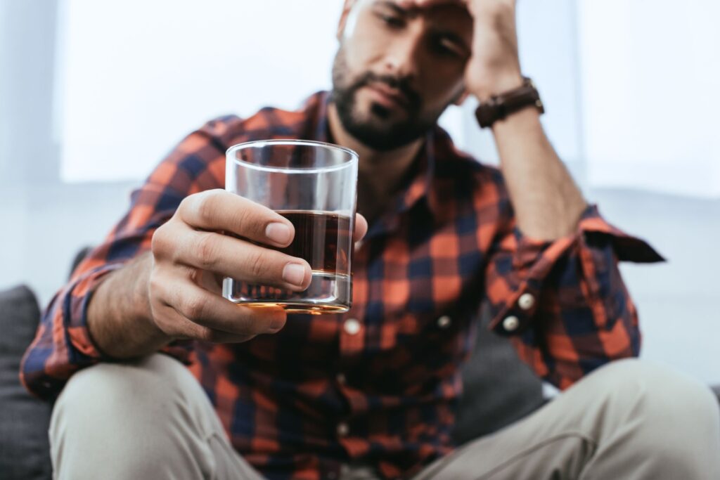 depressed young man with glass of whiskey