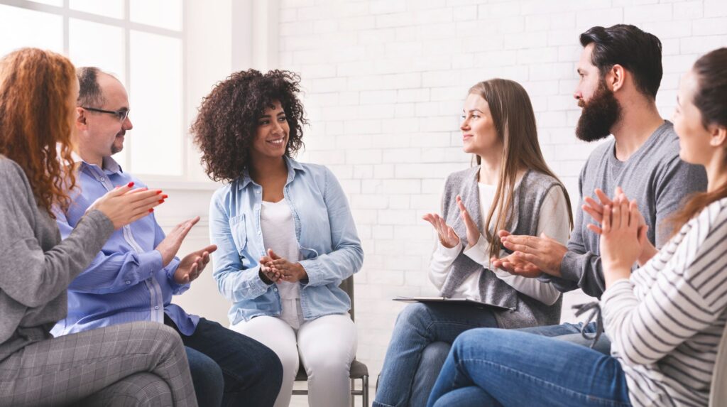 Diverse people applauding to themselves at therapy session in rehab