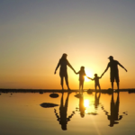 Silhouette of happy family who playing on the beach at the sunset time.