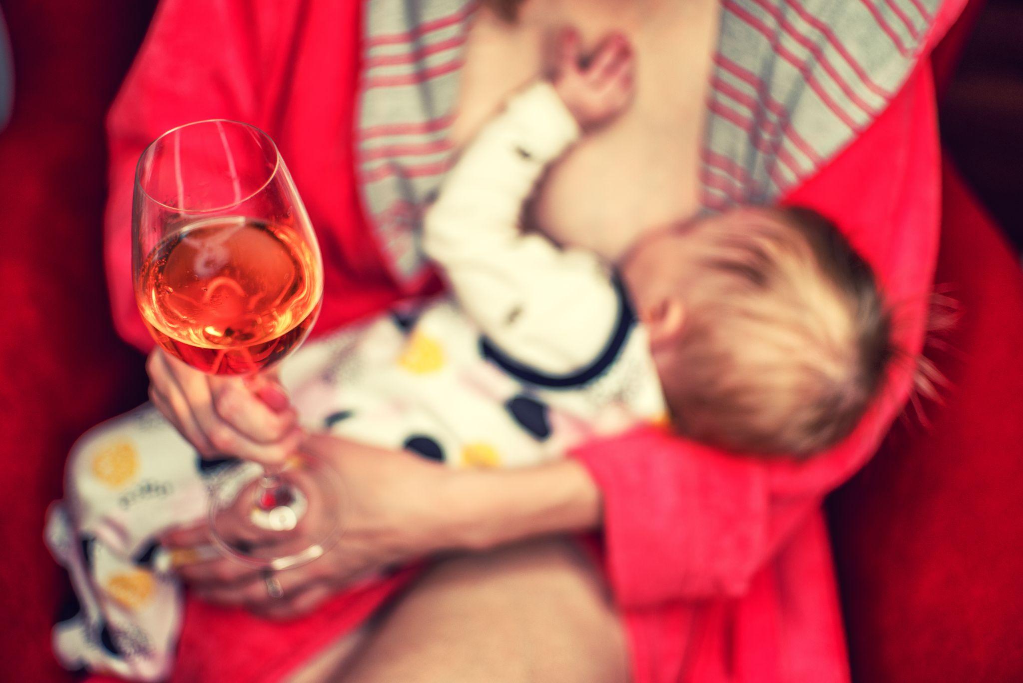 new mom with newborn and glass of wine
