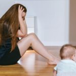 woman sitting on bedroom floor with infant