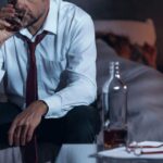 corporate man drinking whiskey in bedroom