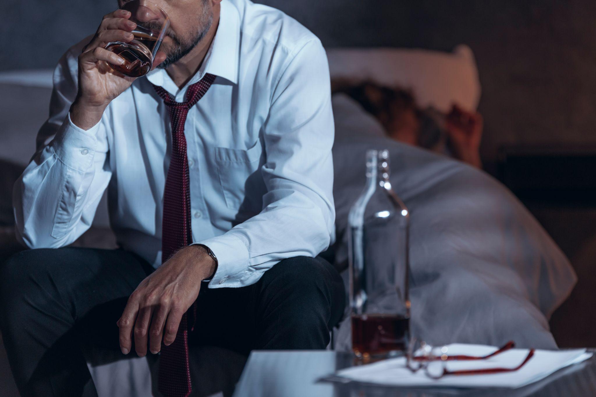 corporate man drinking whiskey in bedroom