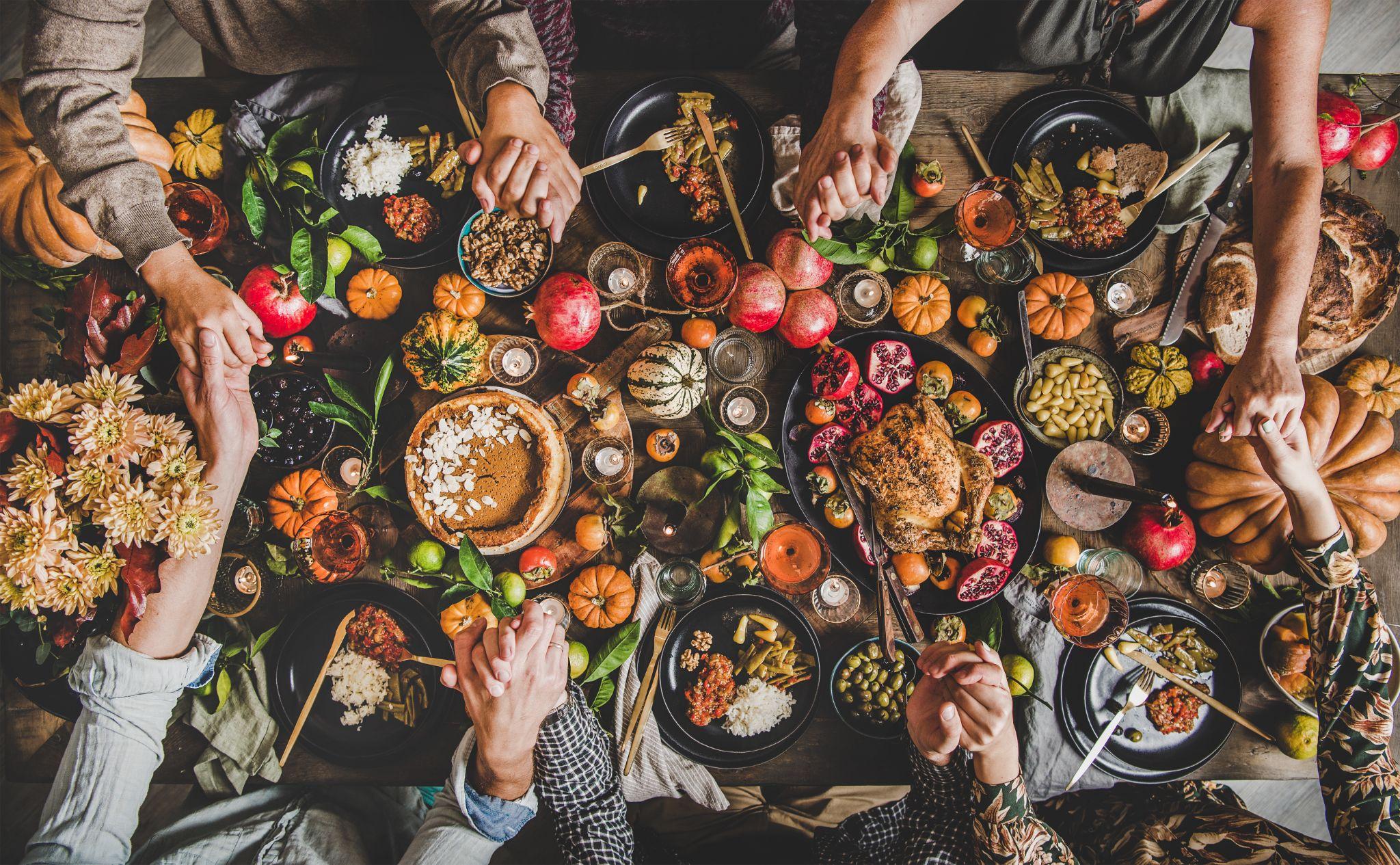 Family praying holding hands at Thanksgiving table.